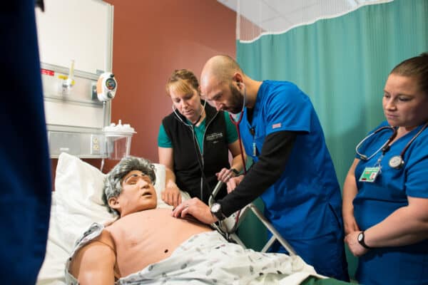 Male nursing student learns how to listen to a heartbeat on a simulation mannikin