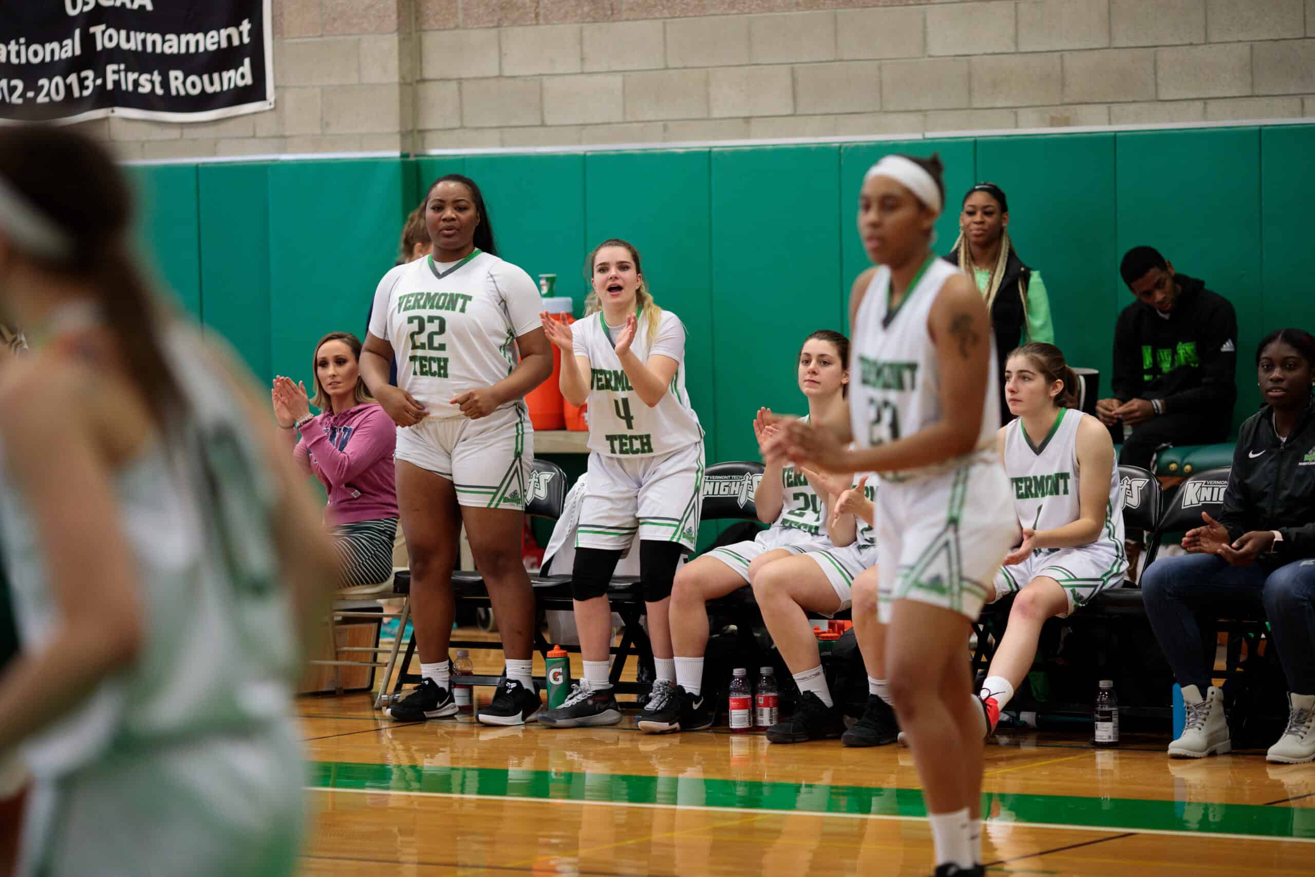 Female basketball players cheer from the bench on the Randolph Center campus