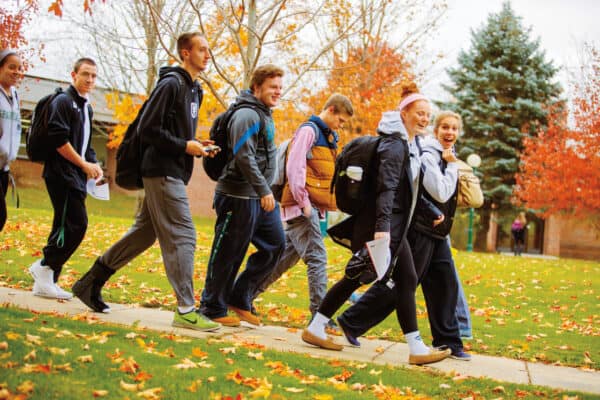 Group of students walk across campus in Castleton during peak foliage