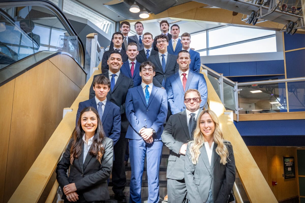 A group of pilot students in professional attire standing on a stairwell at the Burlington airport