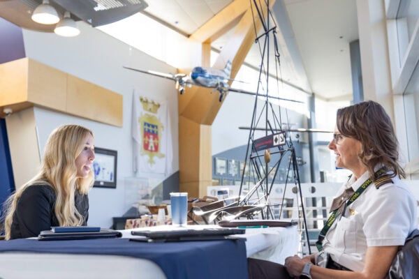 A young woman speaking with a female pilot during a mock interview