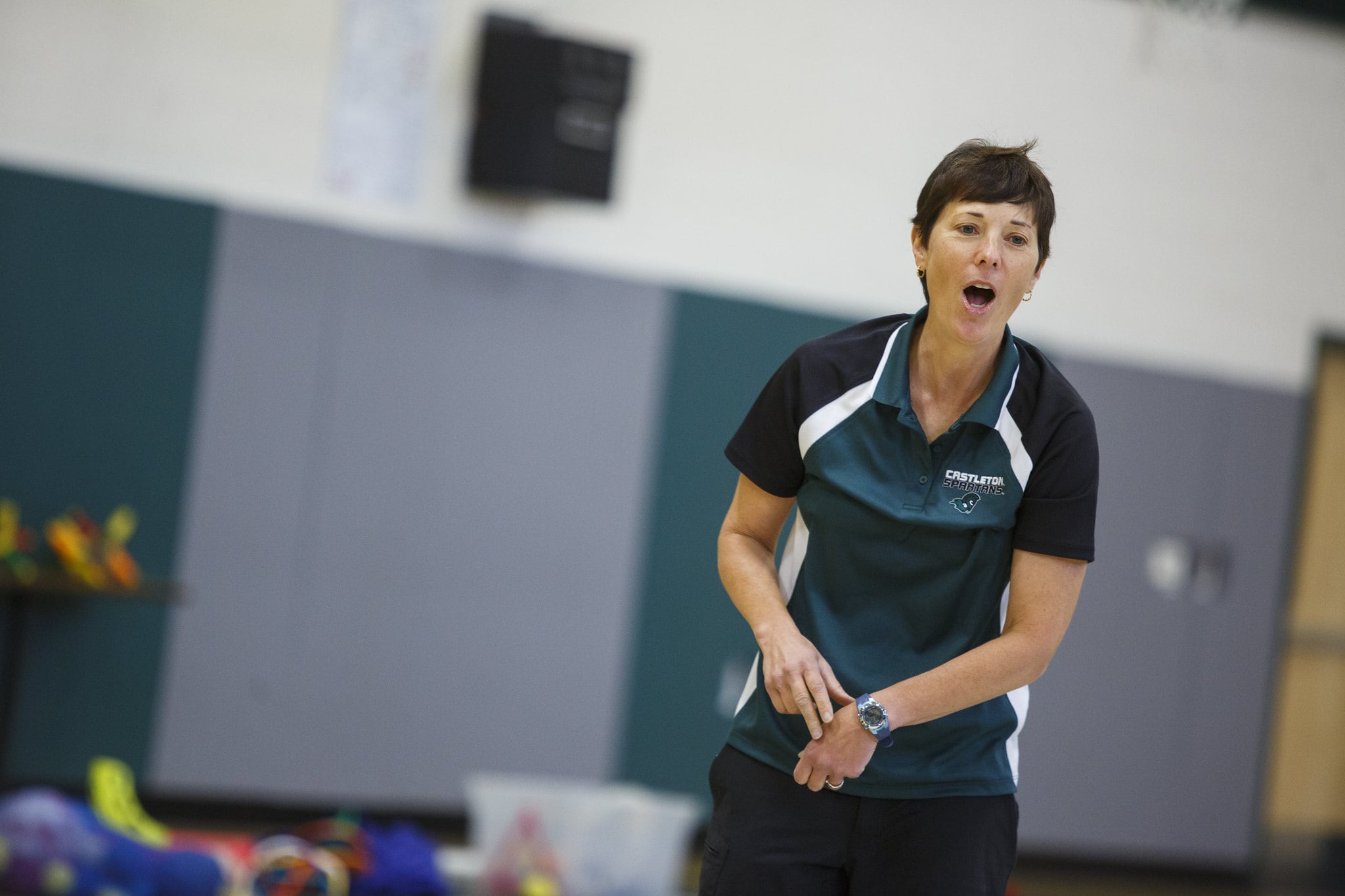 A woman in a green shirt at a Vermont State University gym.