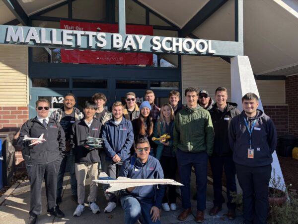 VTSU pilot students posing at the front of Mallets Bay School with model airplanes