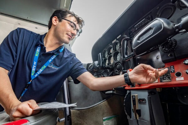 A young man making adjustments inside of an airplane