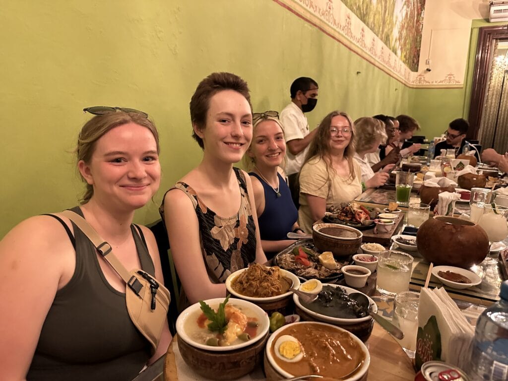 Vermont State University Students sit at a table covered in exotic foods.