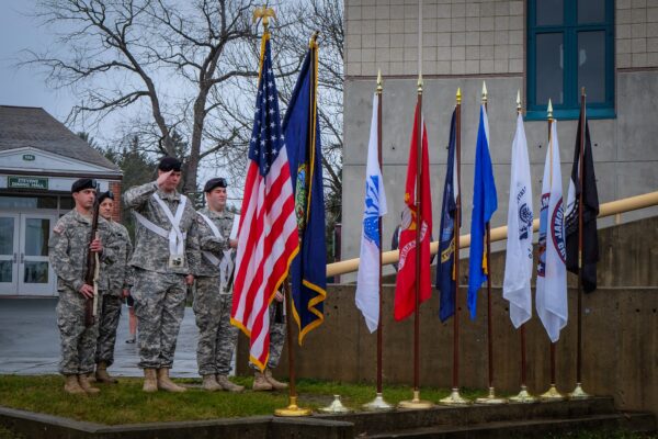 Four soldiers standing and saluting the American flag.