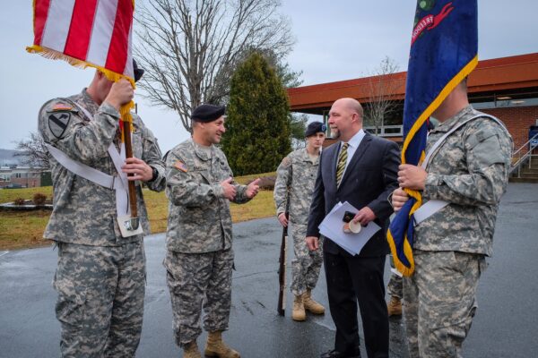 Four soldiers holding flags standing around a man in a suit.
