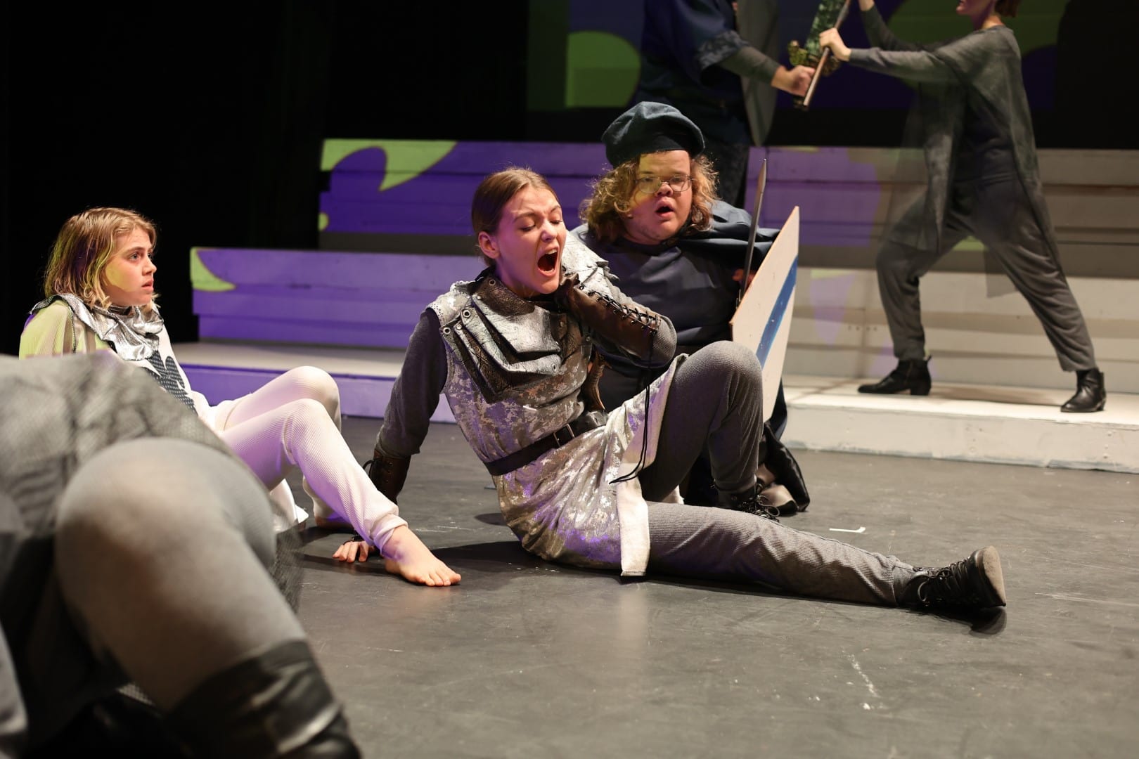 A group of people on stage with a swords in their hands.