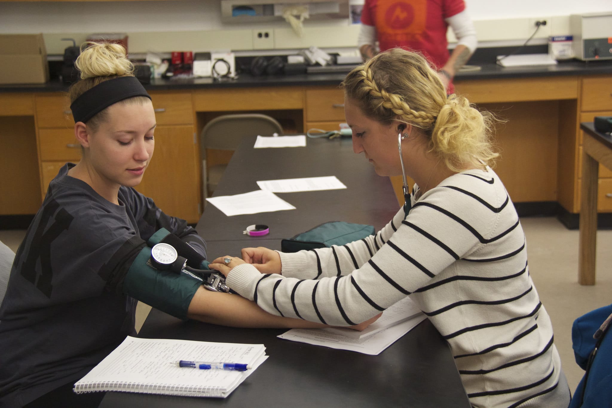At Vermont State University, two women are taking their blood pressure in a lab.