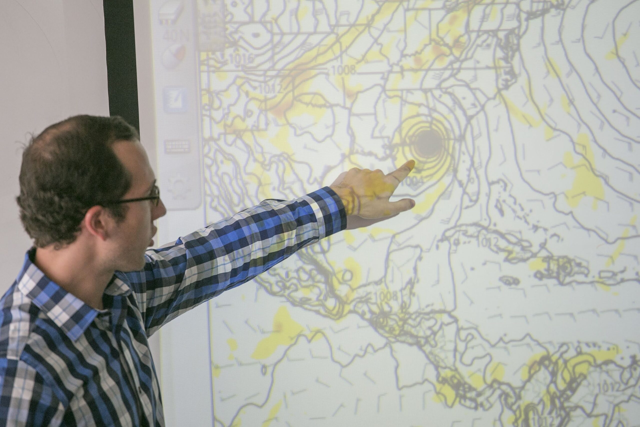 a man pointing at a map on a screen.