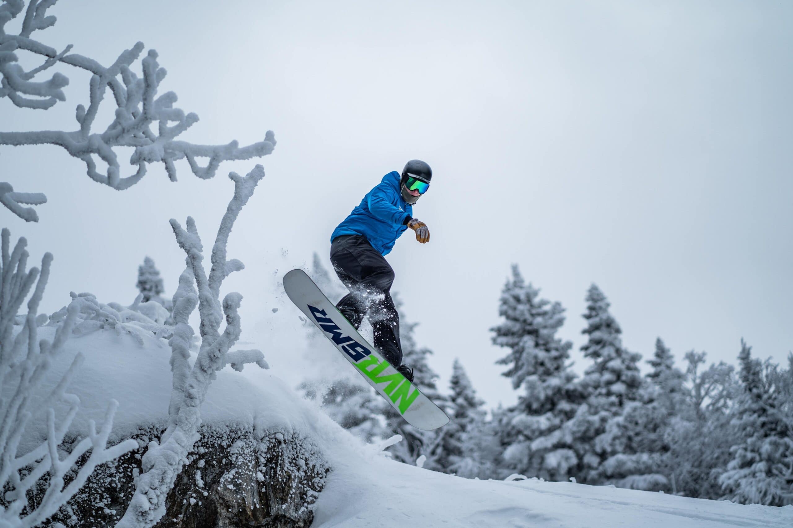 A snowboarder flying through the air over a mound of fresh snow.
