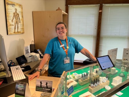 A woman in a blue t-shirt stands behind a counter.