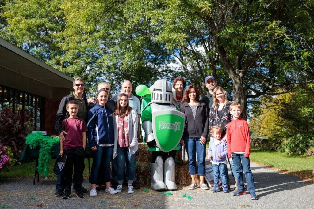 A group of people clustered around a mascot of a knight.