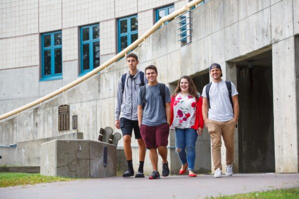 A group of friends walking on a paved path on the Vermont State University Lyndon campus.
