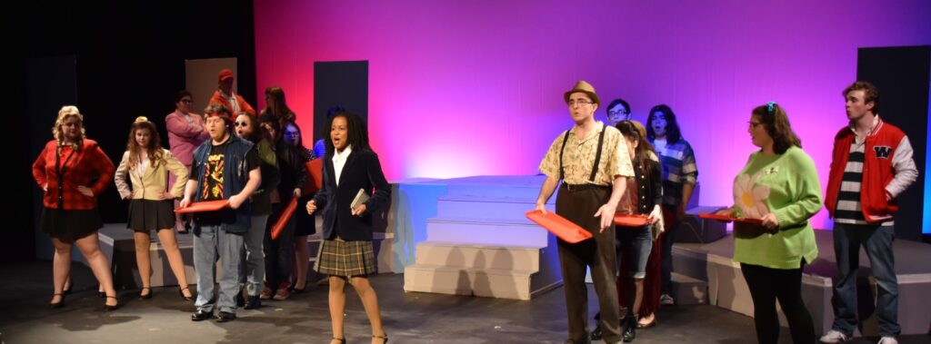 A group of students on a stage performing a play at Vermont State University Lyndon.