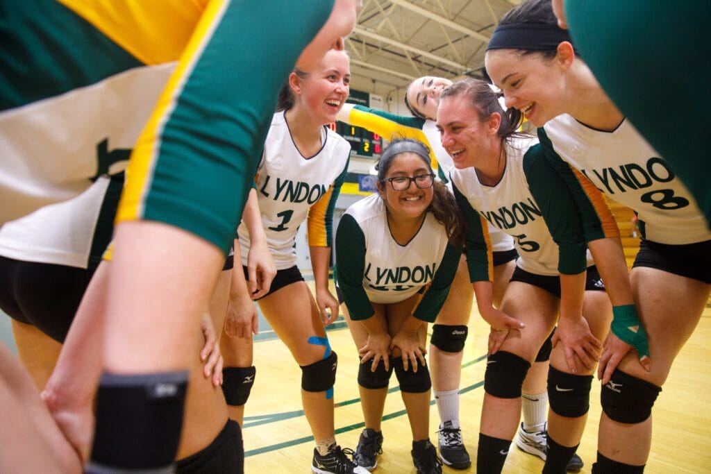 A group of girls in Lyndon jersey's huddle and laugh before a game.