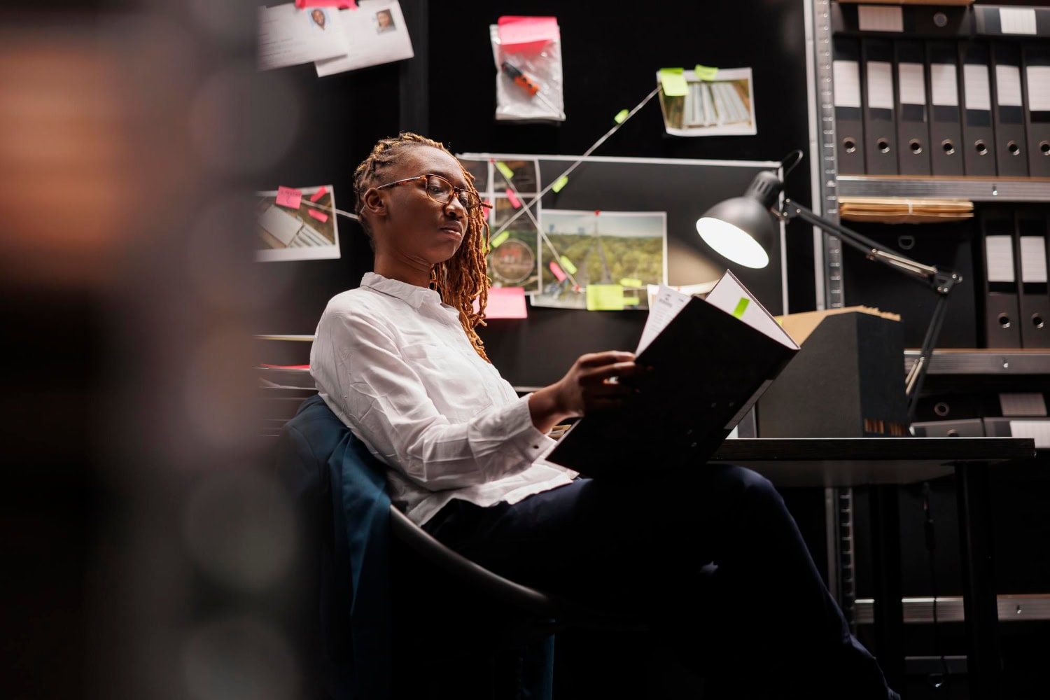 A young woman sitting in a chair and reviewing documents in an investigative office