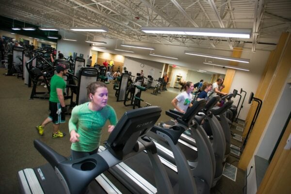 A variety of students working out on exercise equipment in the Vermont State University Randolph gym.