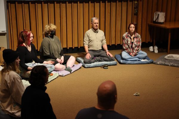 A group of people from the Vermont State University Holistic Health program on the floor mediating in a circle.