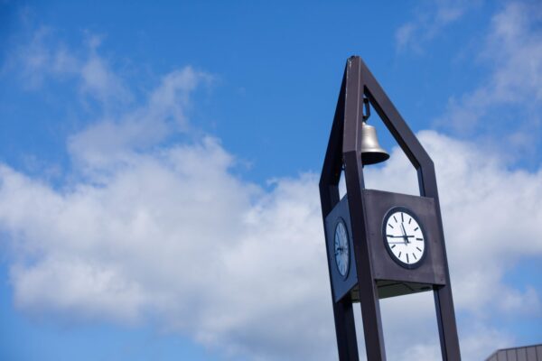 The top of a clock tower against a blue sky on the Vermont State University Campus.