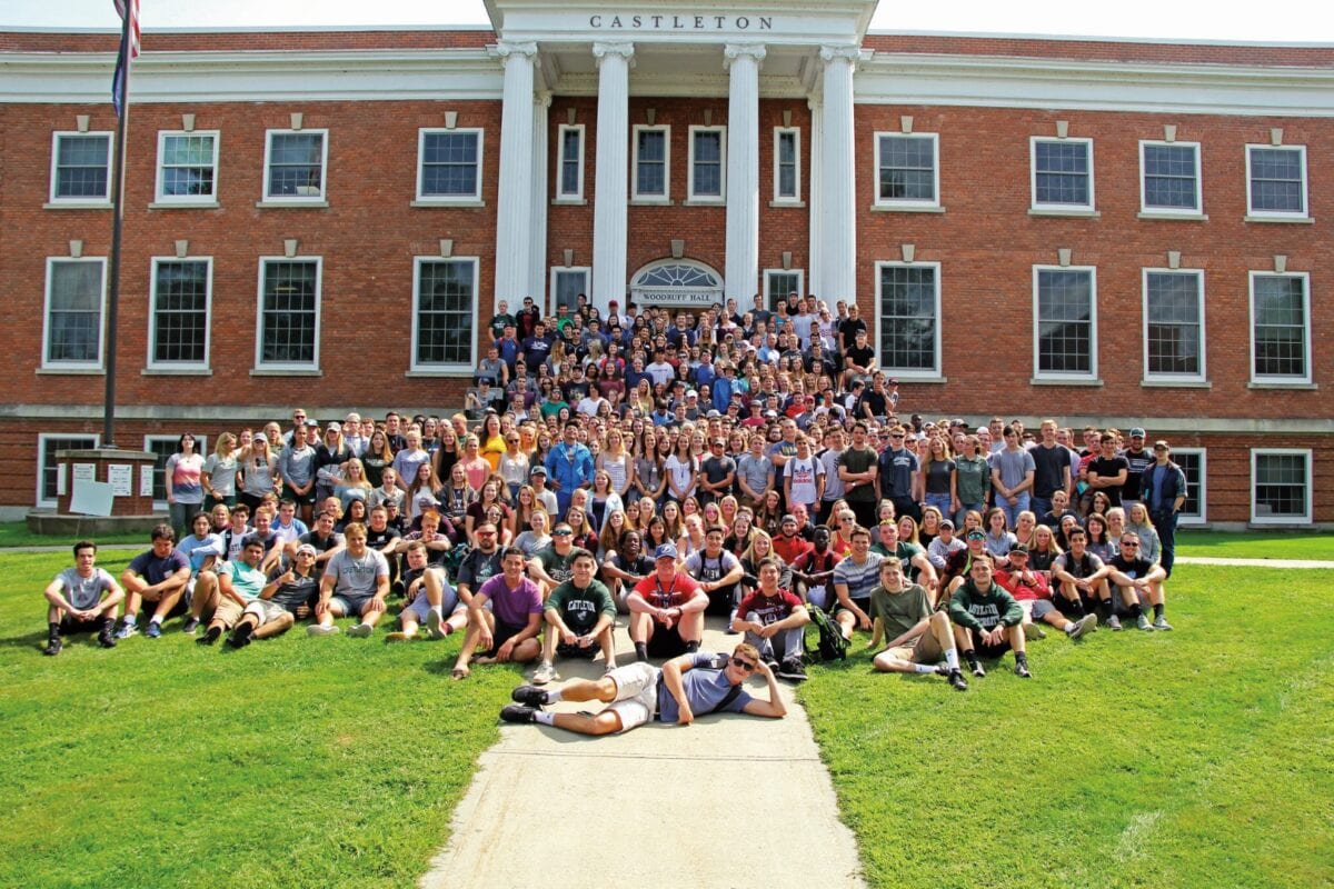A massive group of people pose for a photo outside of a giant bring building on the Vermont State University Castleton campus.
