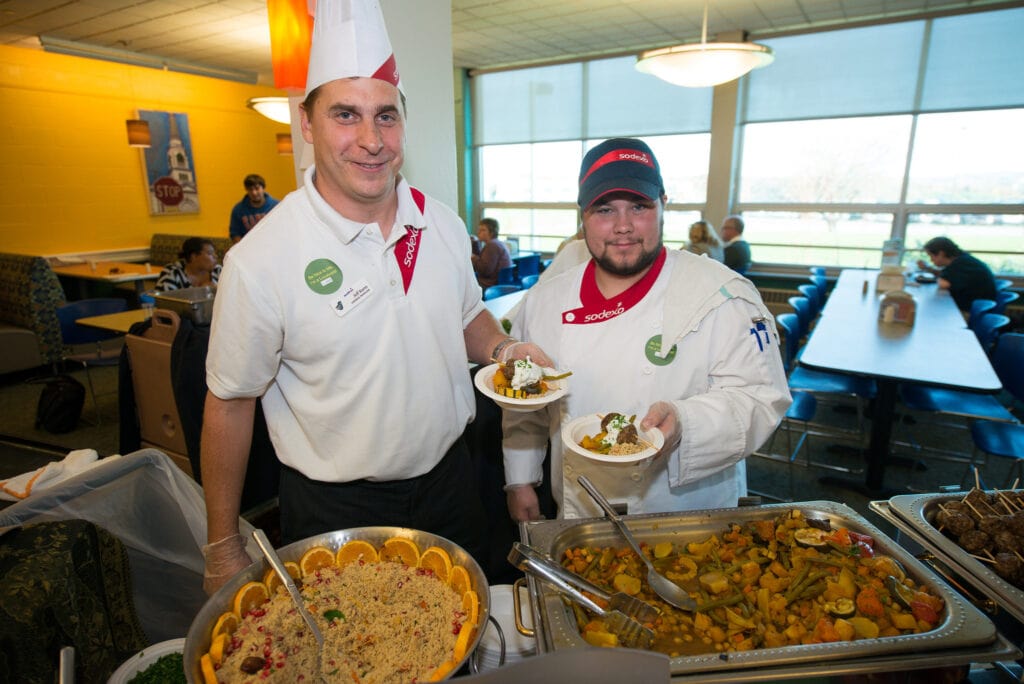 Two chefs hold meals in the dining hall of the Vermont State University Randolph campus.