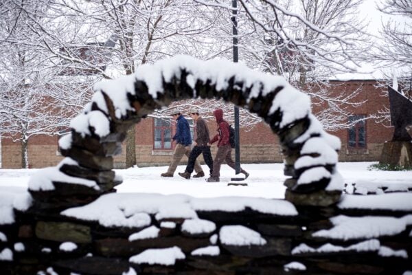 A scenic picture framed in snow of students walking on the Vermont State University Randolph campus.