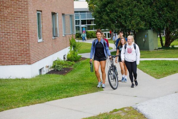 A group of students walk a paved path on the Vermont State University Castleton campus.