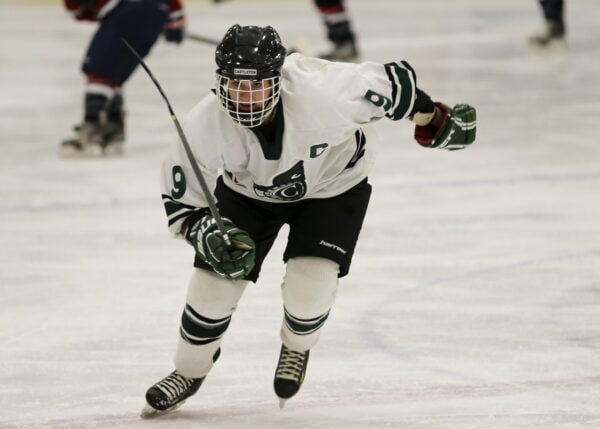 A woman hockey player skates with intense focus in the Spartan Arena.