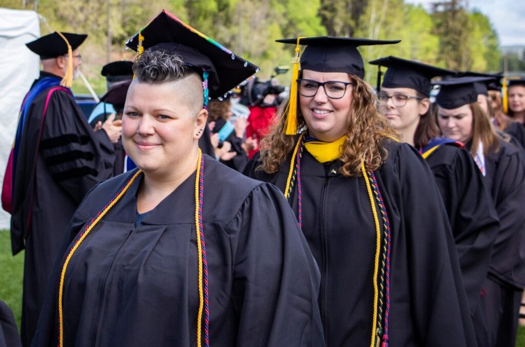 A group of Vermont State University graduates walking in a line at the commencement ceremony.