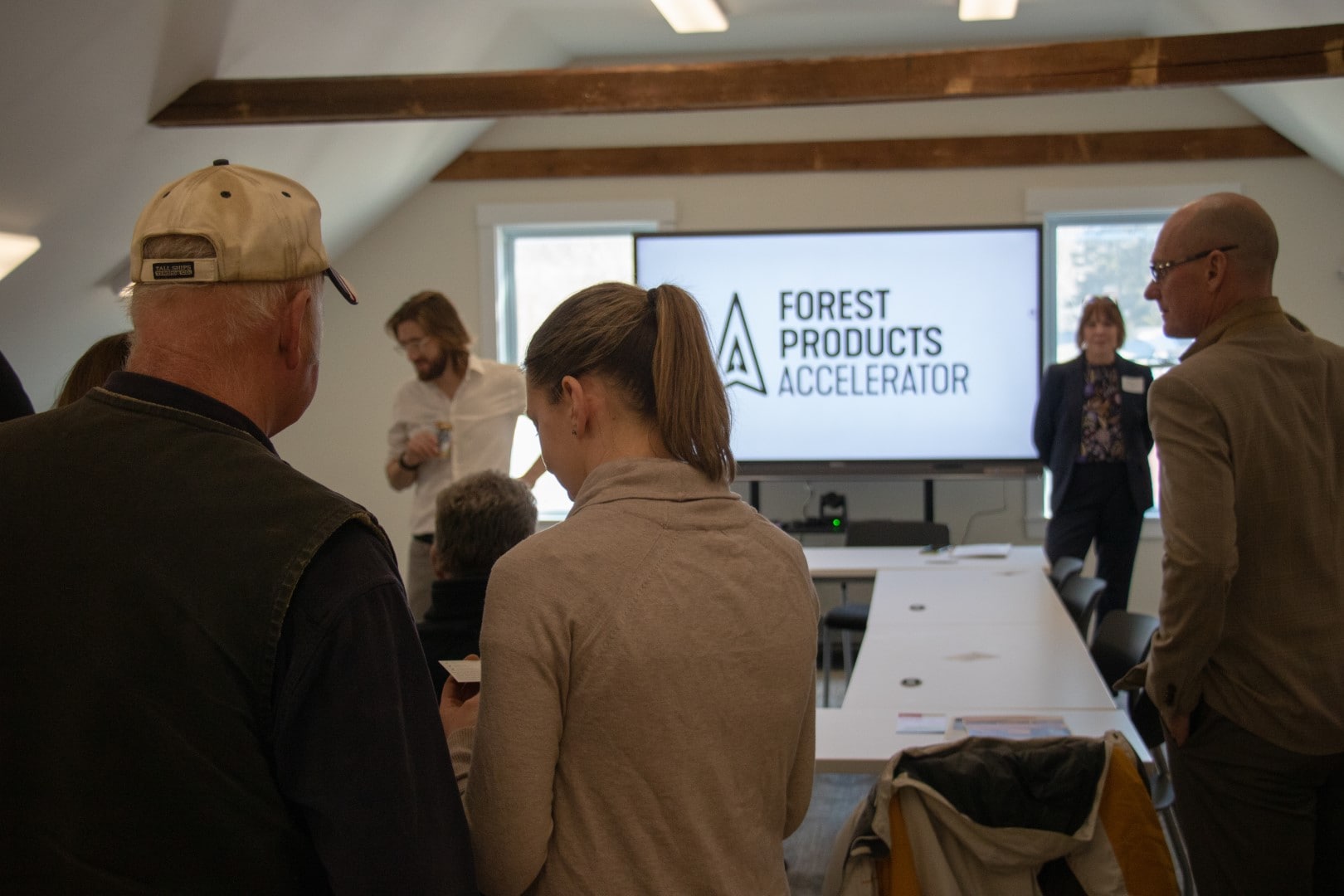 People stand around a table with a tv screen at the head that says Forest Accelerator.