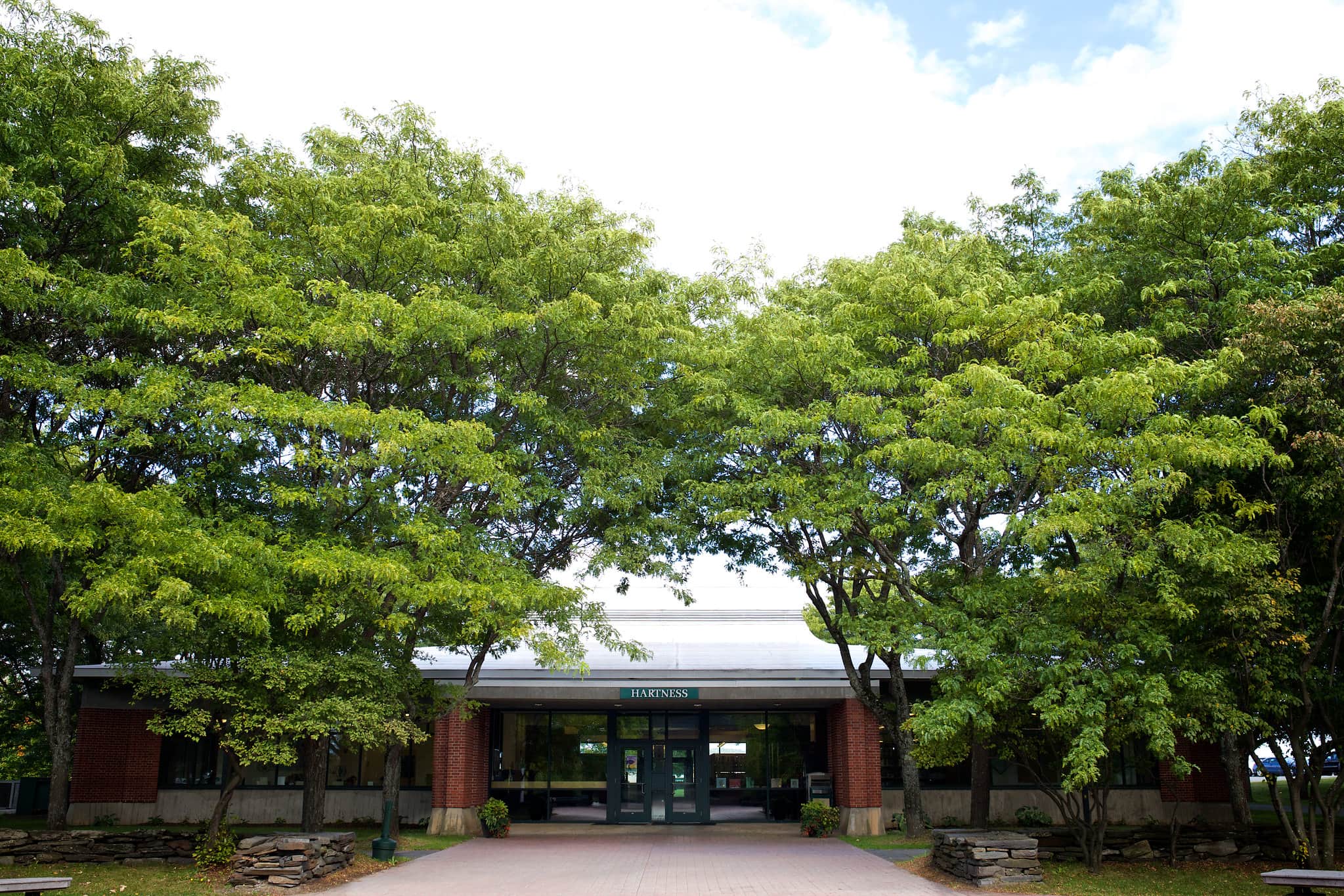 A building that says Hartness Library with green bushy trees framing the entrance.