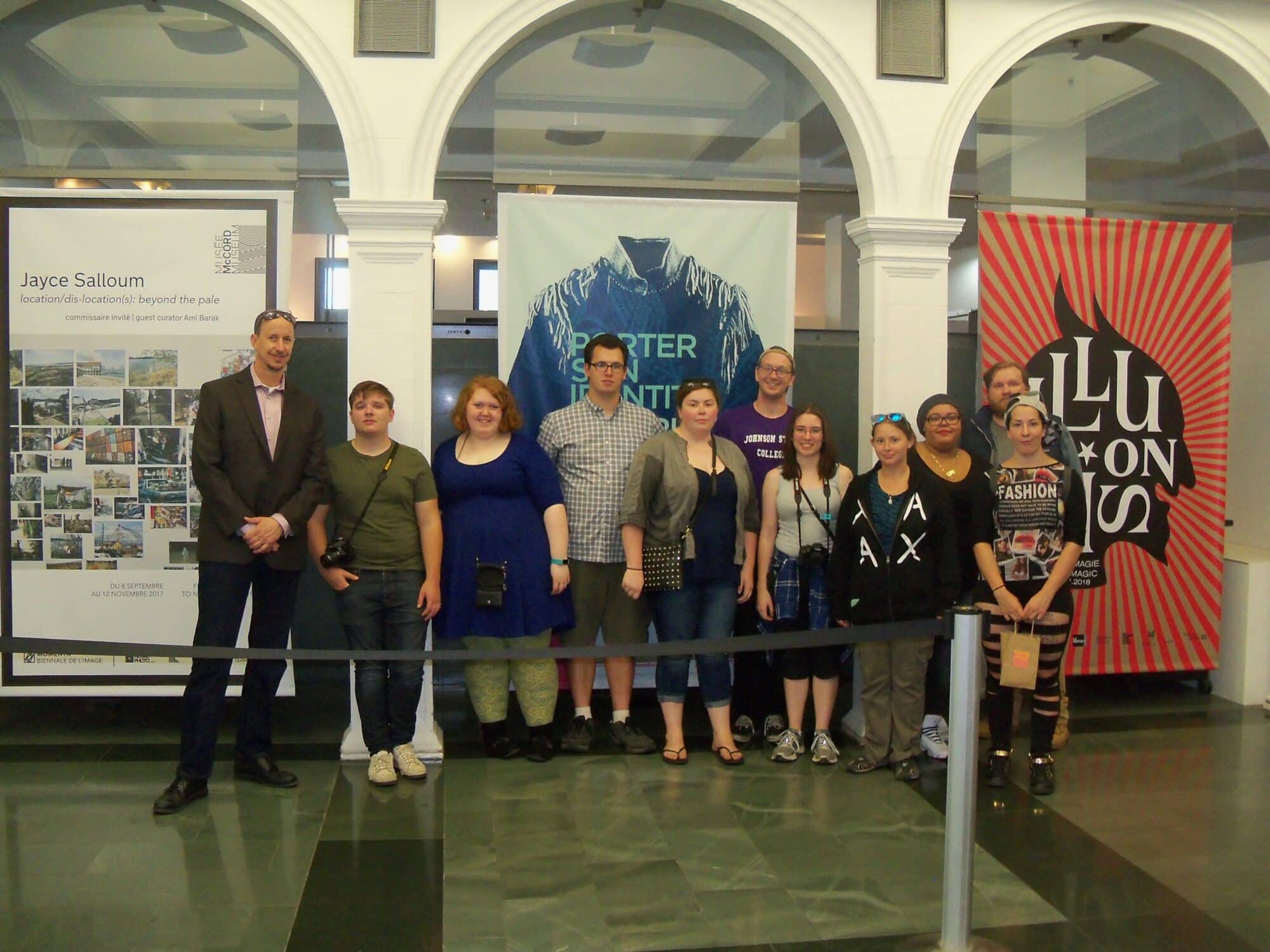 A group of Vermont State University students stand in front of some plaques and smile at the camera.