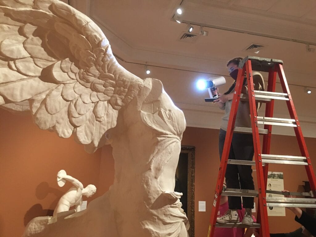 A person on a ladder in the AAG major 3D scans a full-scale cast of Winged Victory of Samothrace at the Berkshire Museum. 