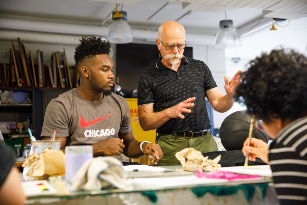 Faculty supports male art student with one-on-one help.