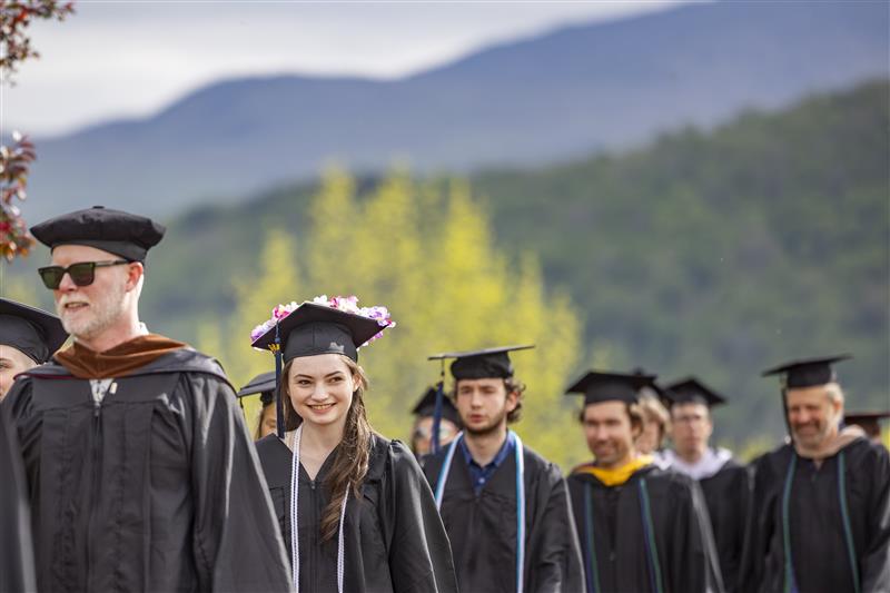 Students lined up outdoors wearing black caps and gowns