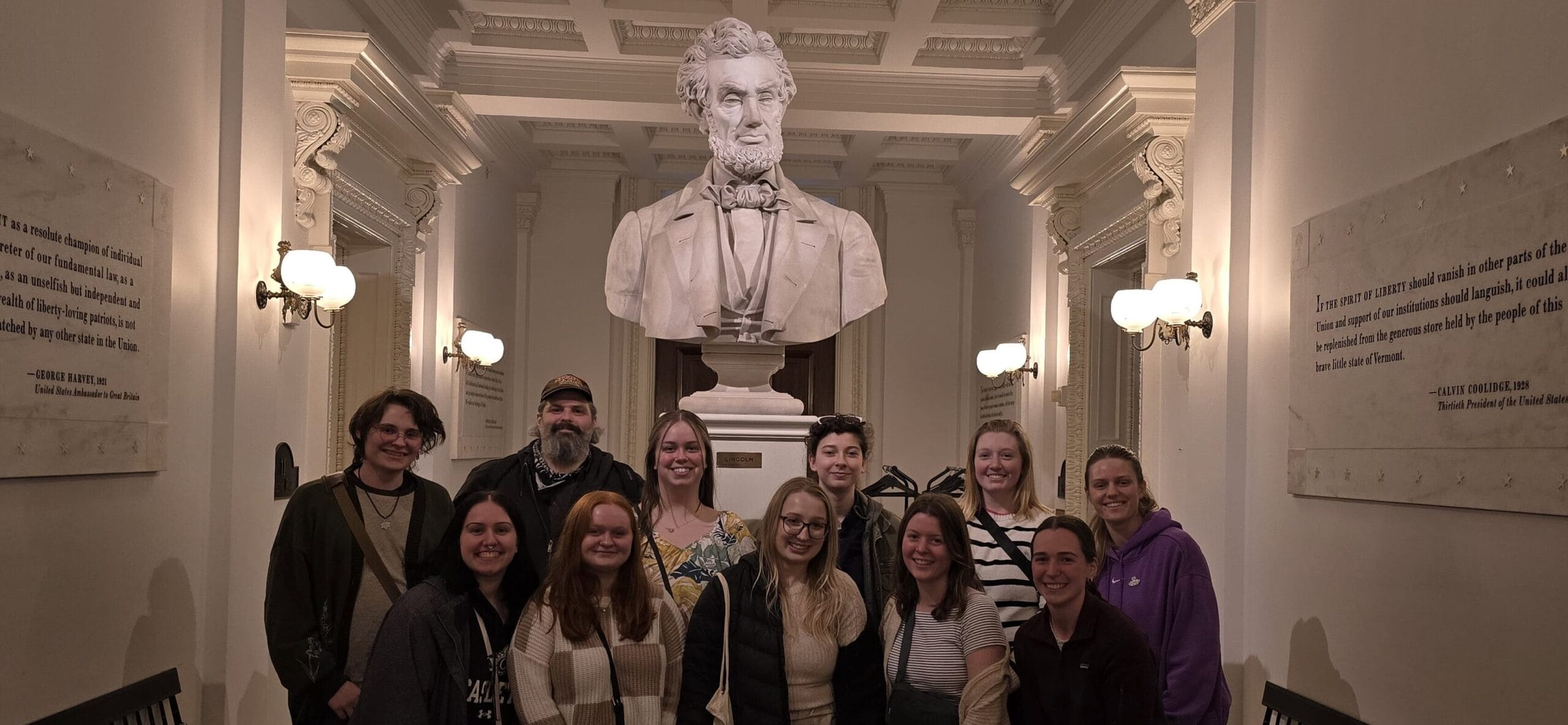 Students smiling in group photo inside state house