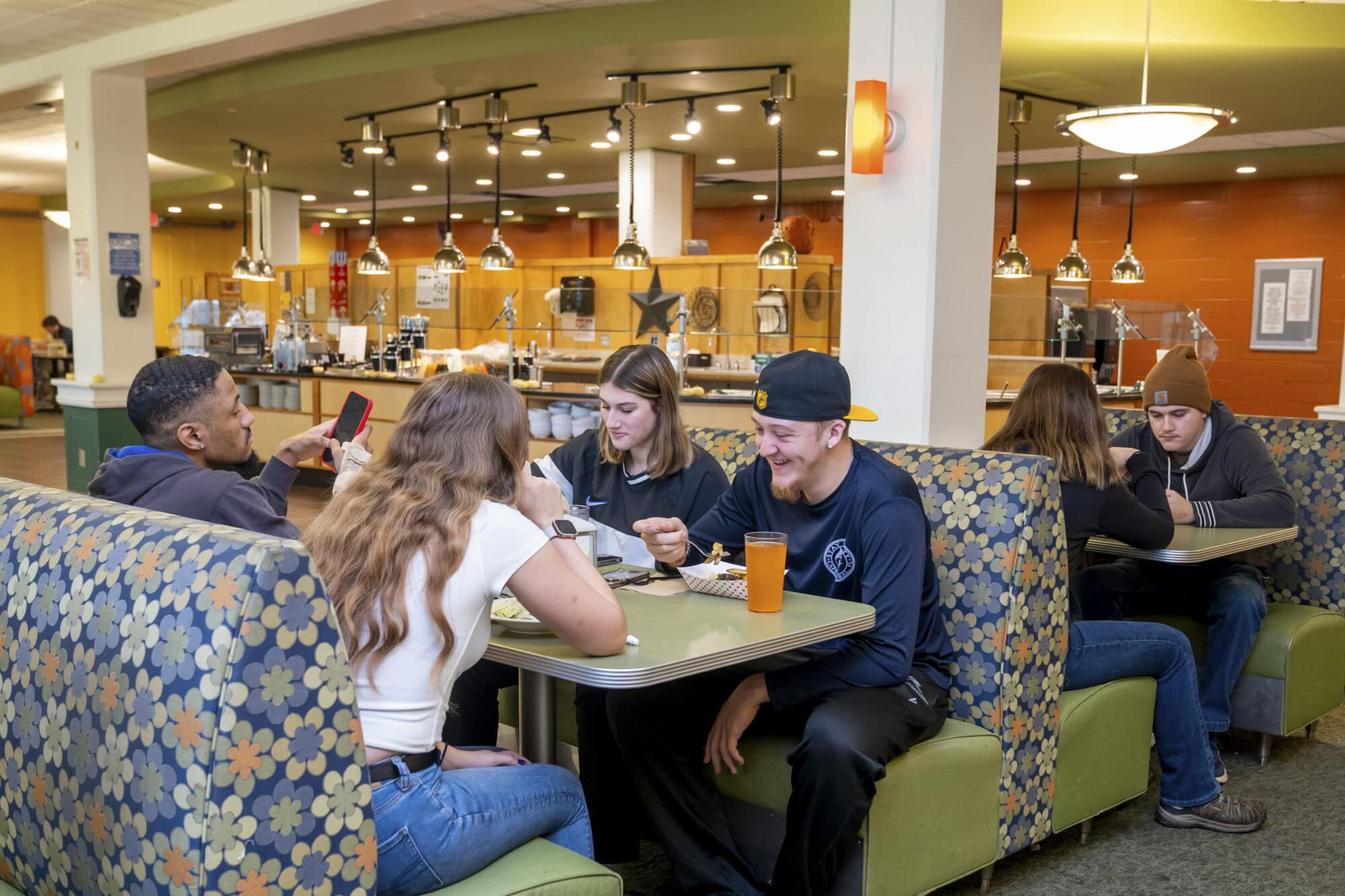 A group of four students seated at a booth style table in the dining hall at VTSU Randolph.