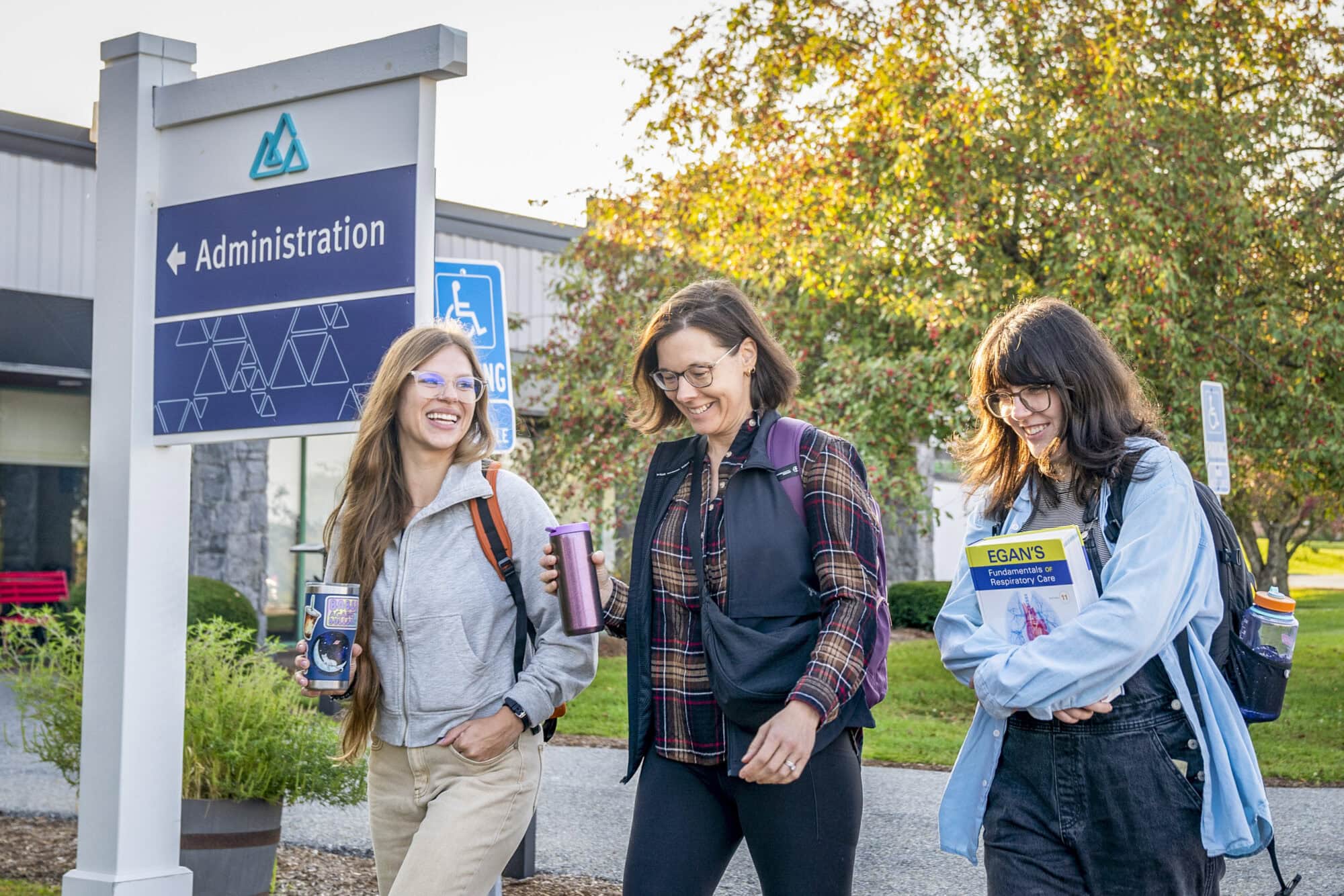Three women walking in front of the Admin building at VTSU Williston