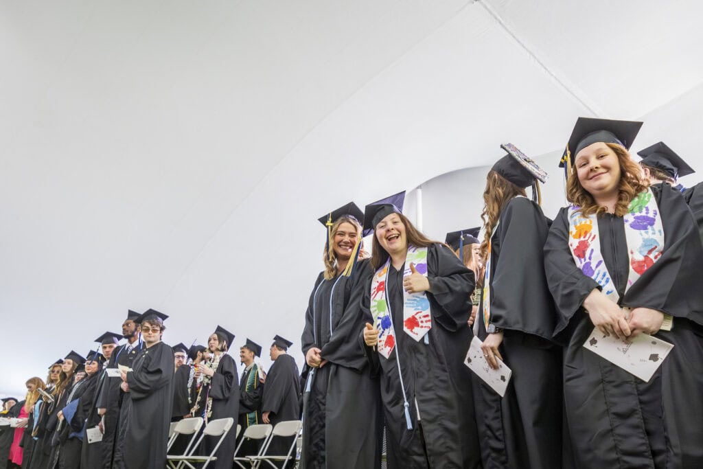 A group of young women smiling at the camera as they stand and wait to approach the stage at VTSU Lyndon.