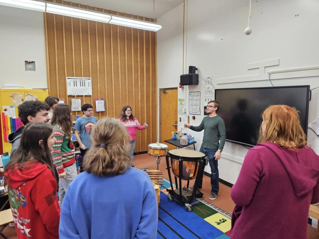 A VTSU Castleton music student conducts a group of middle-school students through a vocal exercise.