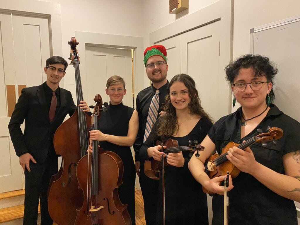 Members of the VTSU string ensemble posing with their instruments and smiling.
