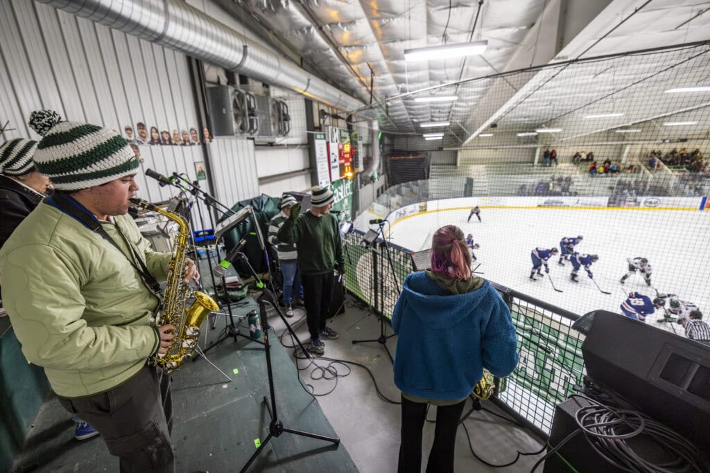 The Spartan spirit band performing at a Men's Hockey game. They are set up in a balcony overlooking the rink.
