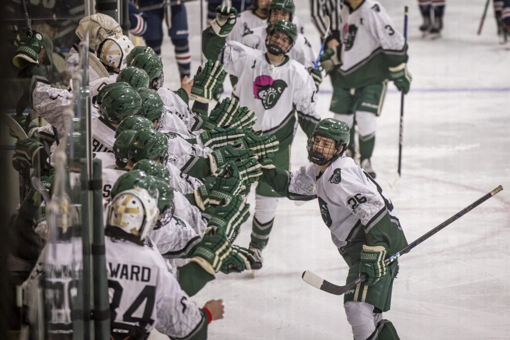 Castleton men's hockey team giving high fives down a long line of teammates.