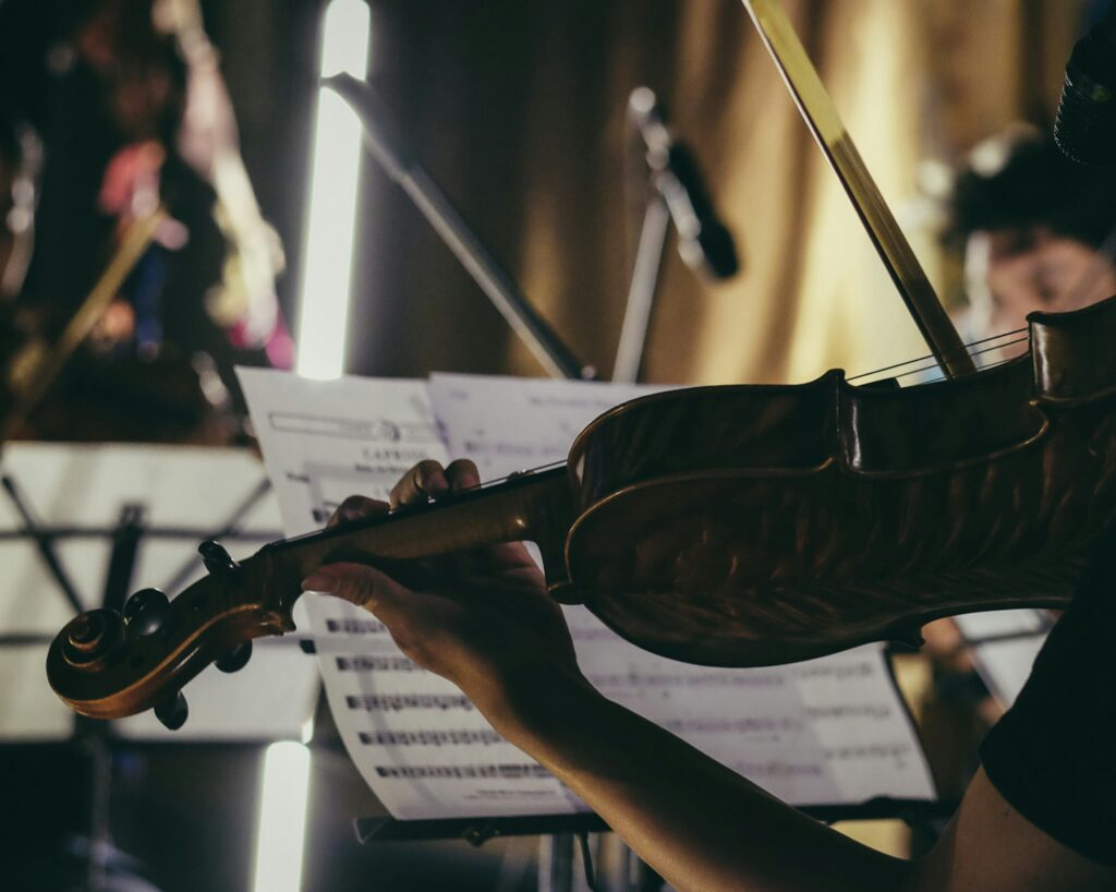 a close up photo a violinist in shadow, with sheet music set up on a stand in front of them.