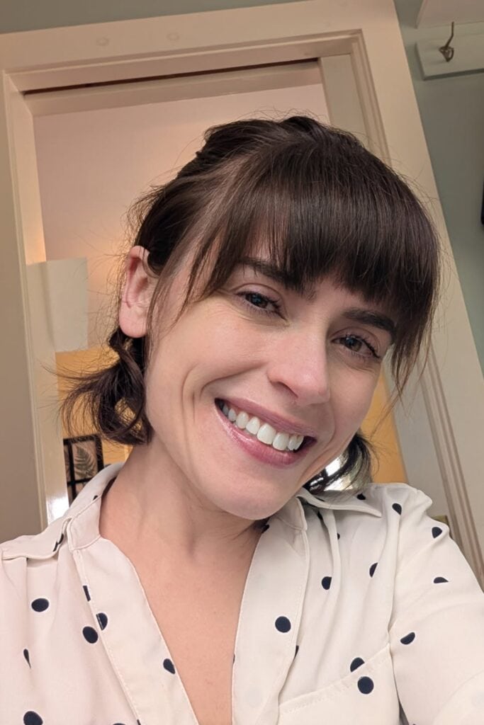 Nicki D'Agostino, a woman with short brown hair, is wearing a spotted shirt and smiling at the camera