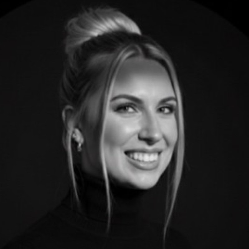 A black and white photo of Melinda Lathrop, a woman with blonde hair tied up in a bun, smiling at the camera.