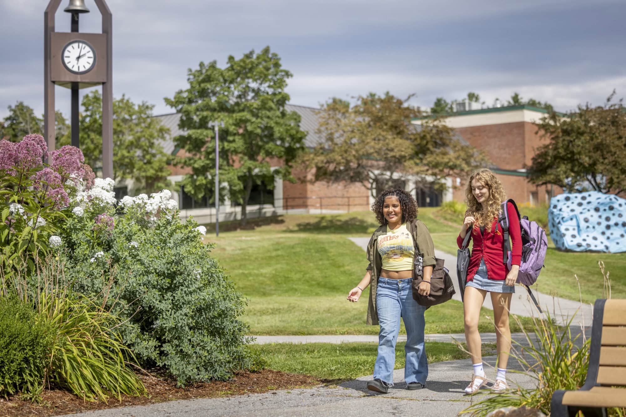 Two young women walking on a path through VTSU Johnson on a sunny fall day
