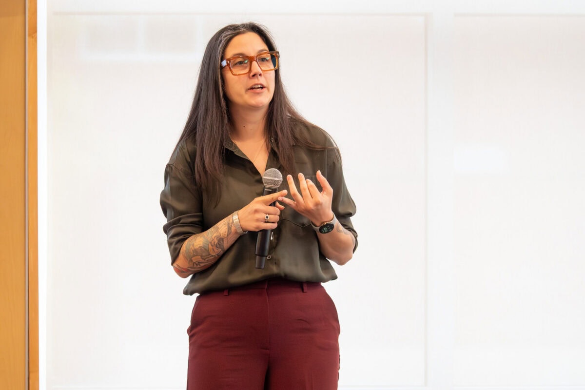 A young woman standing and holding a microphone while presenting research