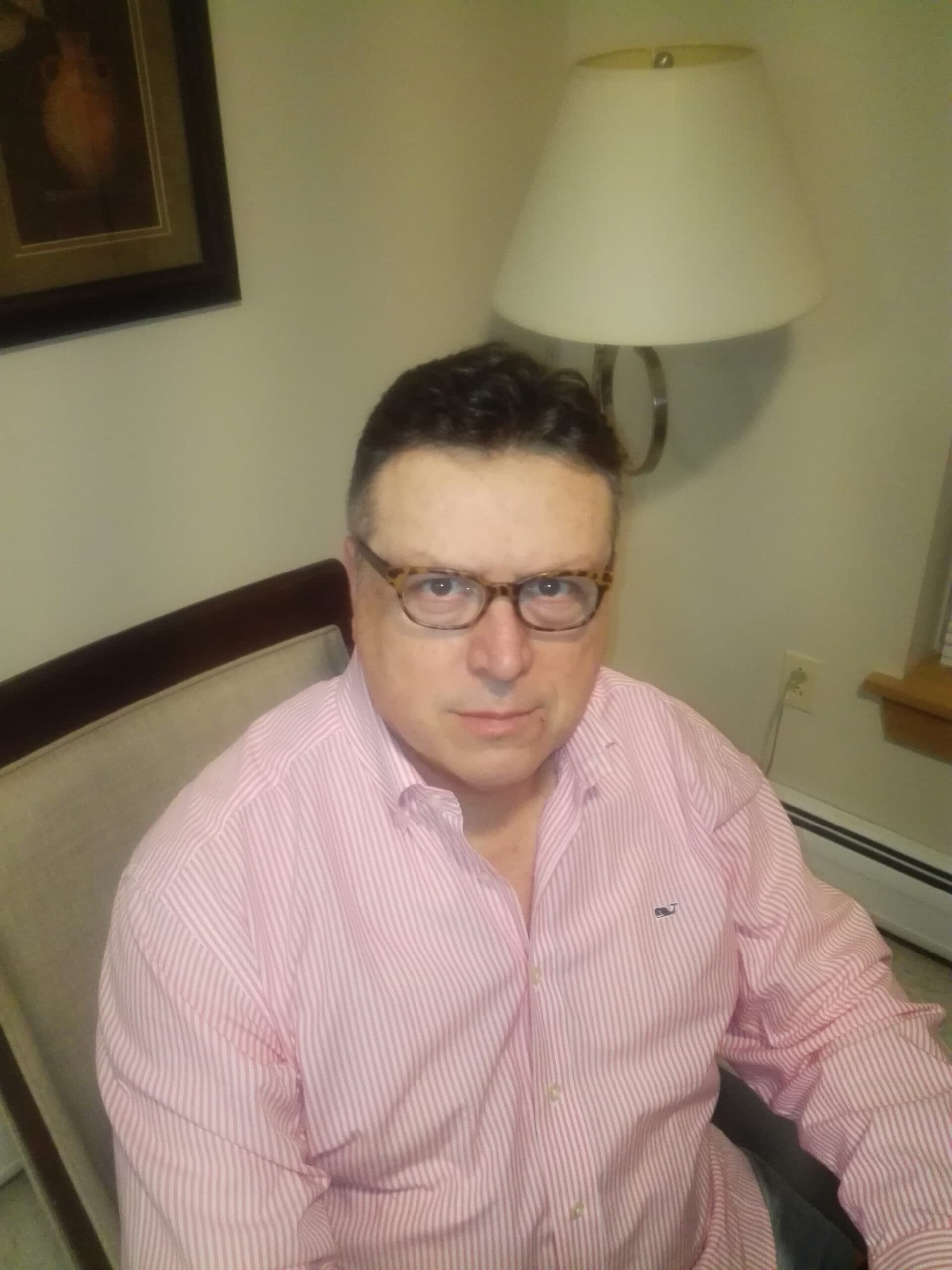 Horacio Tavaglini wearing a pink button-up shirt and looking directly at the camera from a seated position